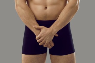 torso of man in black underwear with hands clasped in front of crotch