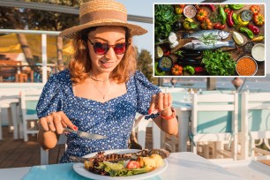 Happy woman with baked sea bass fish in a seafood restaurant. The Mediterranean diet is an indispensable source of omega-3 fats and vitamins