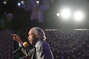 Rev. Al Sharpton speaking into a microphone during a Martin Luther King Jr. Day rally at Metropolitan AME Church in Washington, DC